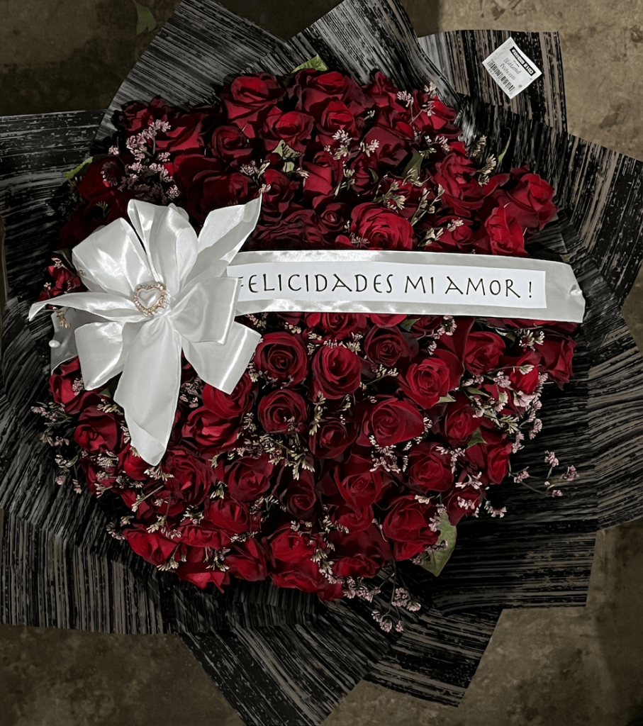 Bouquet of red roses with a white decorative ribbon that reads 'Felicidades mi amor!'